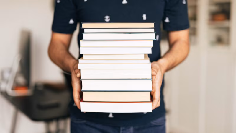 A man carrying a tall stack of books