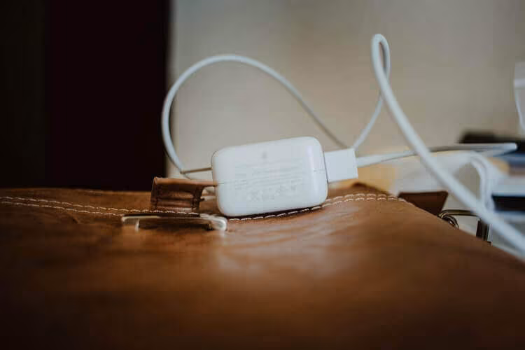 A white phone charger plugged in on a wooden table