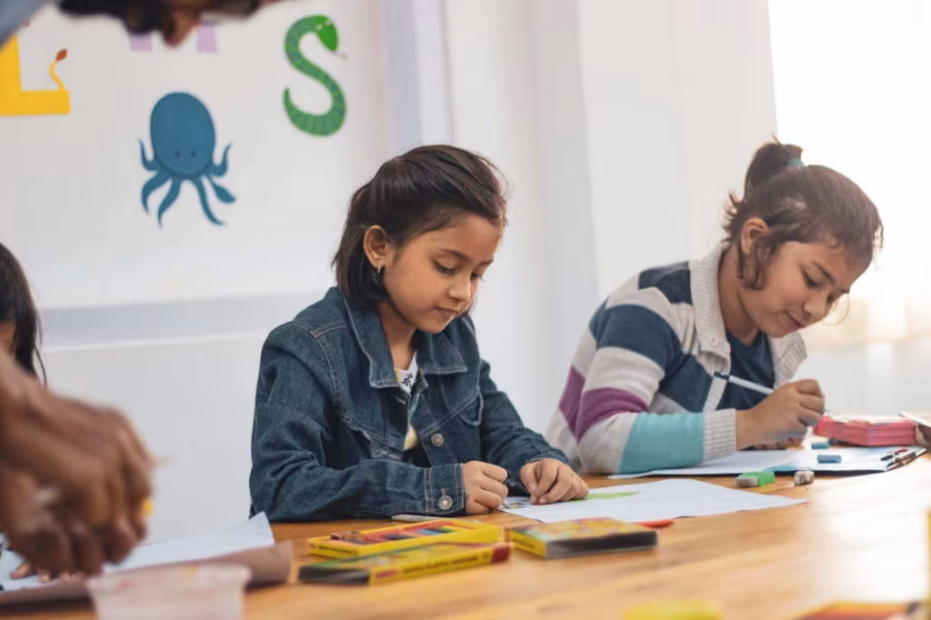 Two children drawing at a classroom table