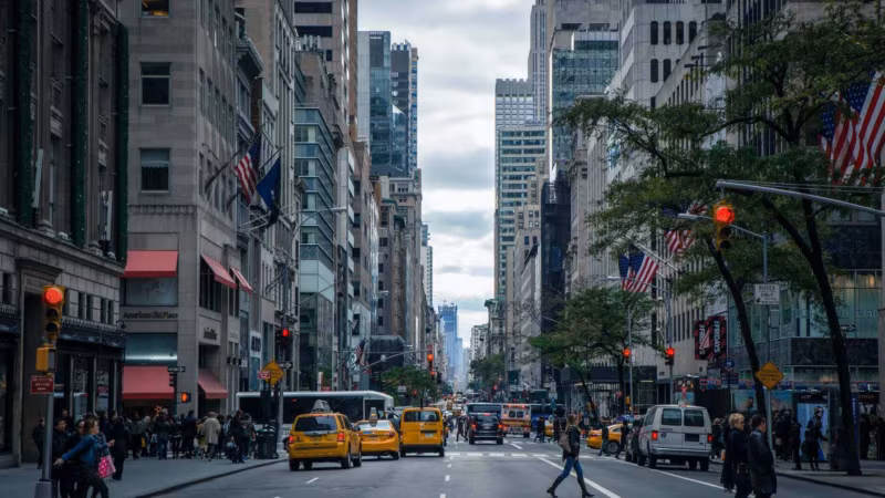 A busy city street with yellow taxis and flags hanging from the buildings