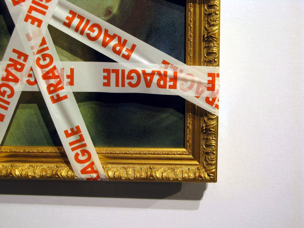 A gilt picture frame criss-crossed with red Fragile tape