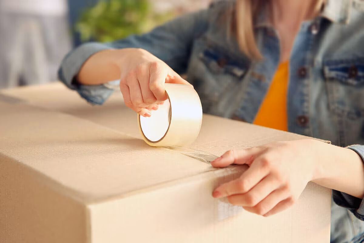 Hands taping a cardboard box shut