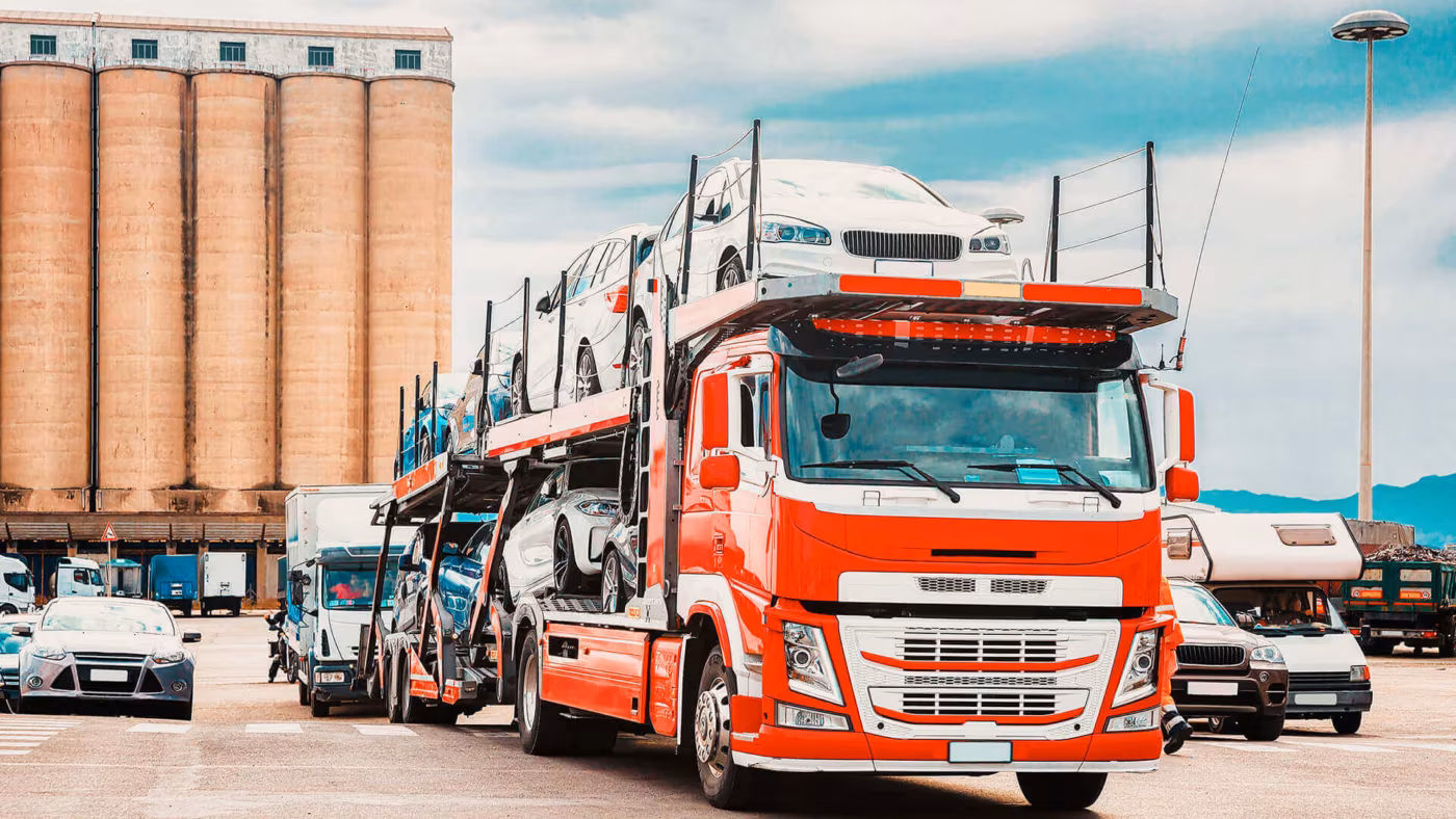 A red car transporter lorry loaded with cars at a depot