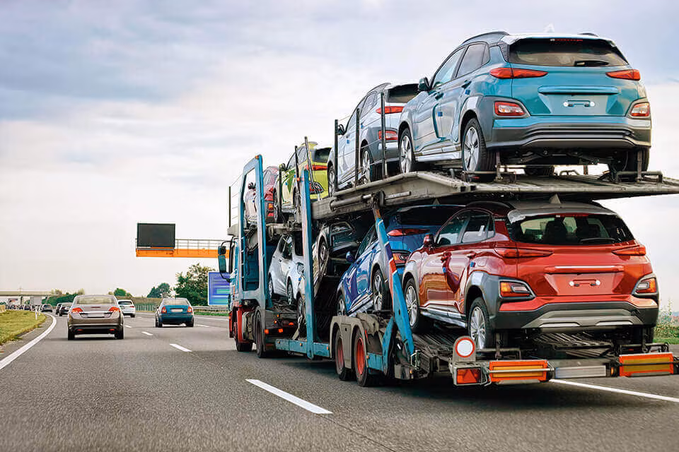 A car transporter carrying several cars on a motorway