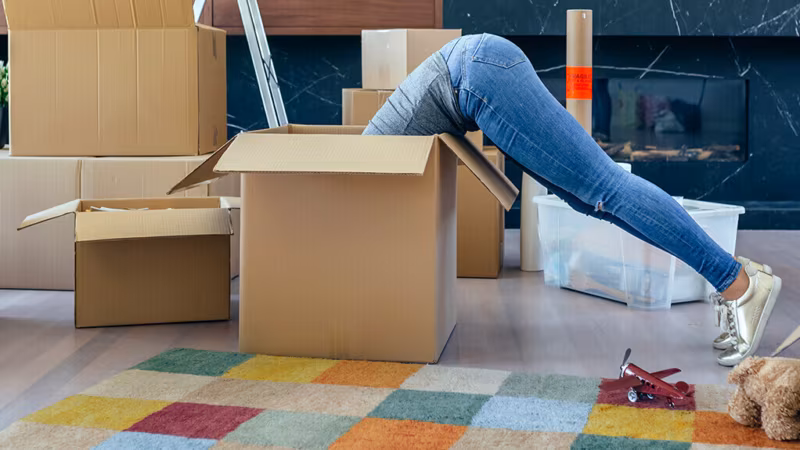 A person diving head-first into a large cardboard box in a child's room