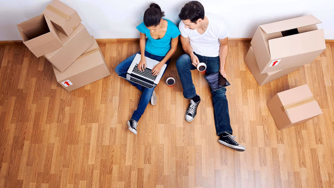 Two people lying on the floor between cardboard boxes, seen from above