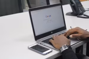 Man googling on a laptop with phone on the side