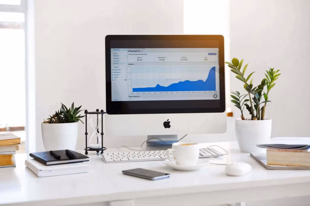 A tidy desk with a computer showing a chart, houseplants and a coffee cup