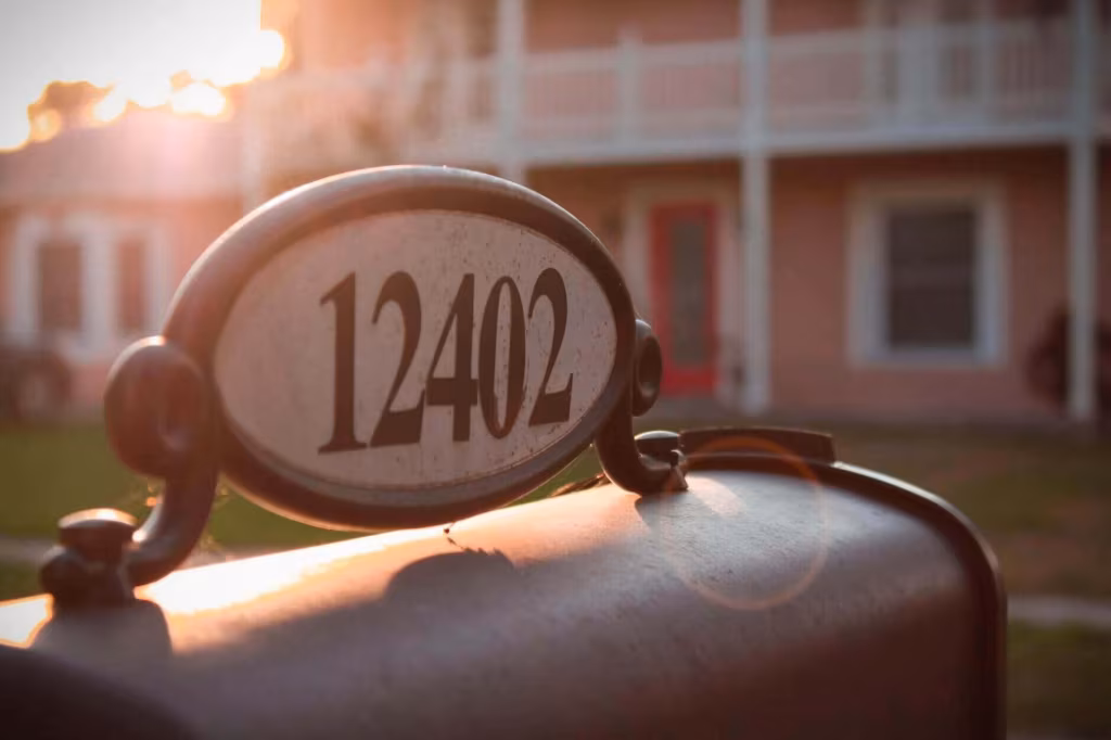 A house number plaque reading 12402 on a curbside mailbox in front of a house