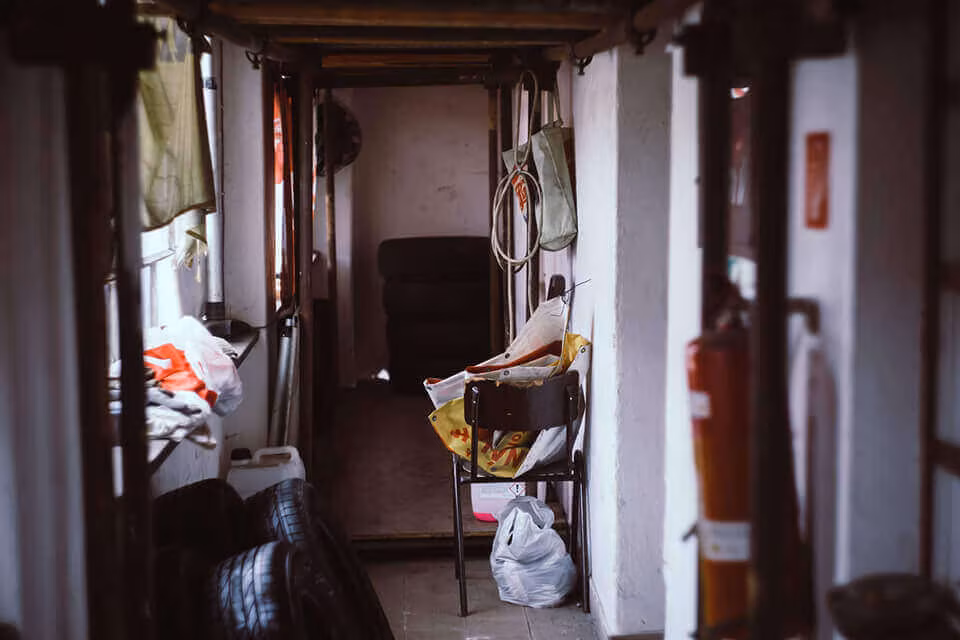 A cluttered narrow hallway with belongings piled along it
