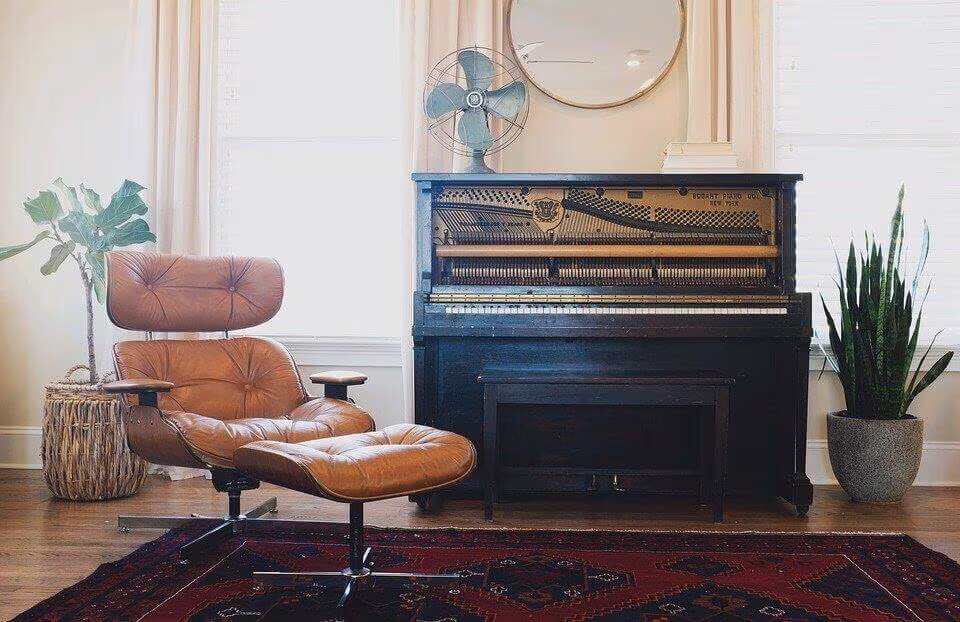 An upright piano and a leather lounge chair in a bright room with a patterned rug
