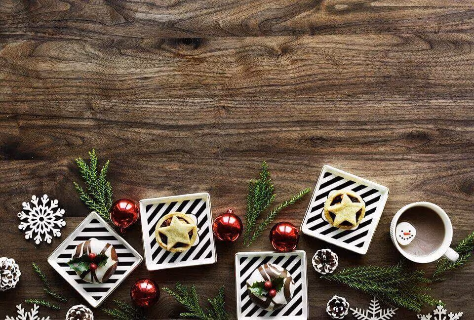 Christmas baubles, gift tags and fir sprigs laid out on a wooden surface
