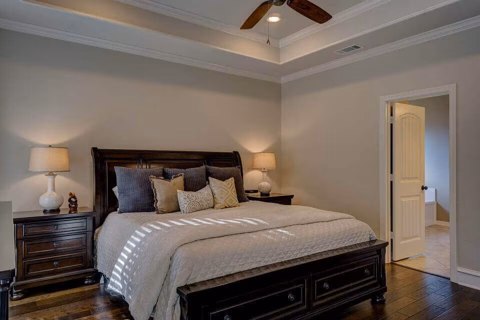 A bedroom with a dark wooden bed, matching nightstands, lamps and a ceiling fan