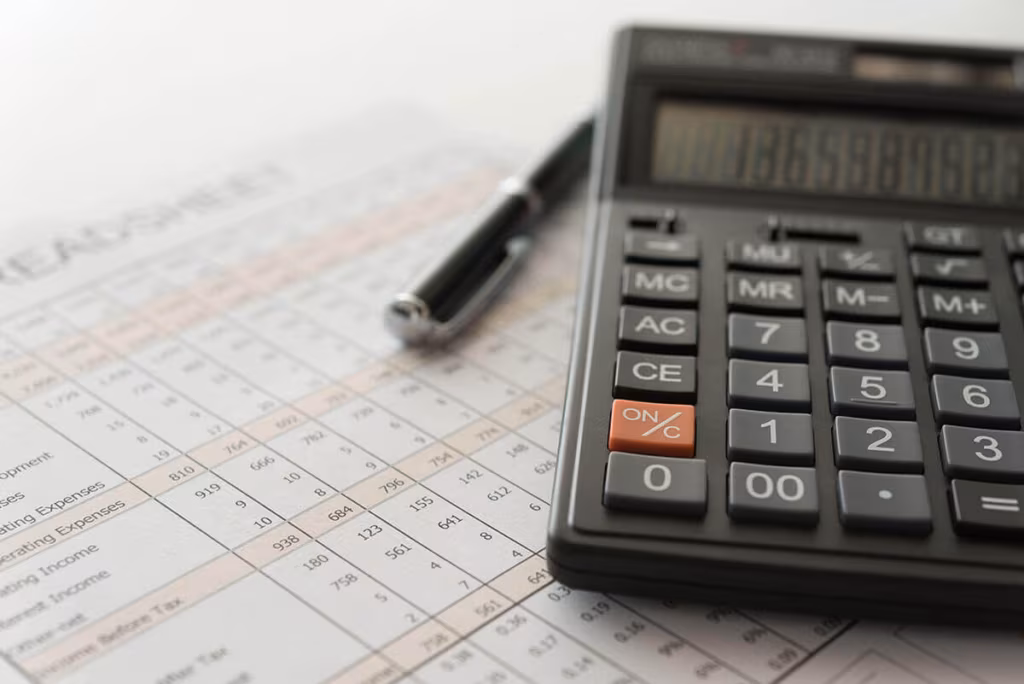 A calculator and a pen resting on a printed spreadsheet