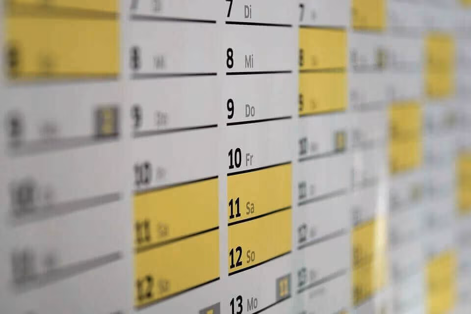 Close-up of a wall calendar with dates highlighted in yellow