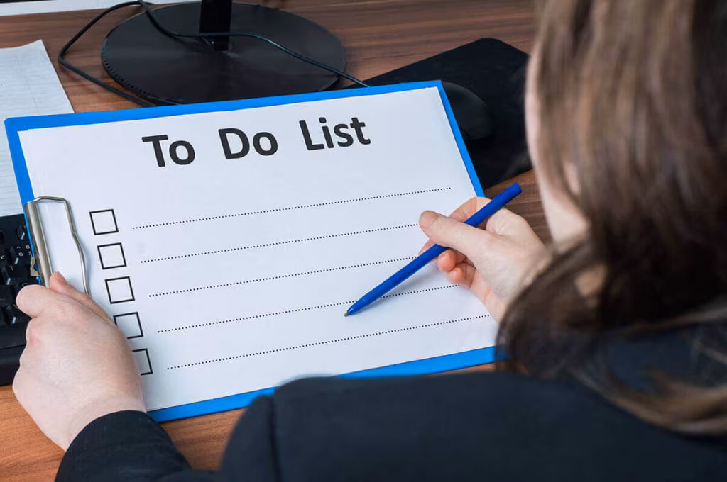 A woman writing on a blank to-do list on a clipboard