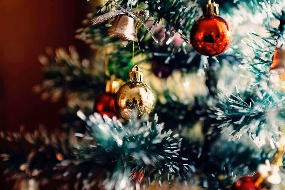 Close-up of a Christmas tree branch with red and gold baubles and small bells