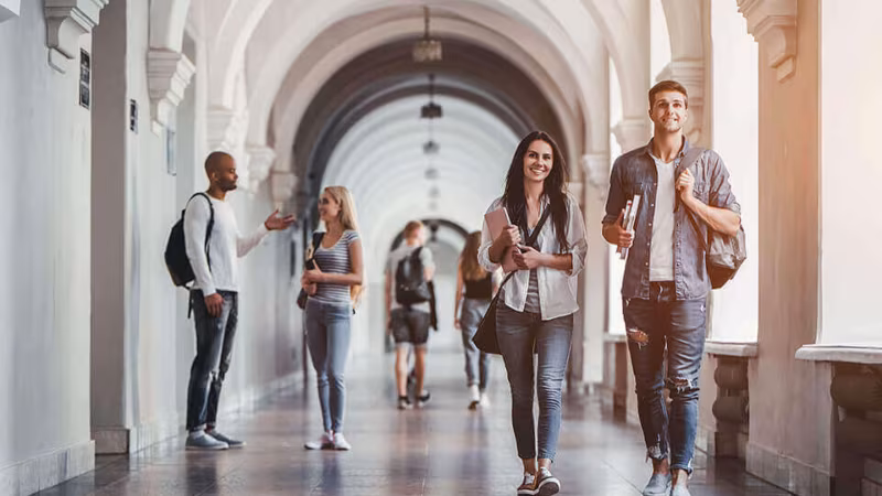 Students walking through an arched college corridor