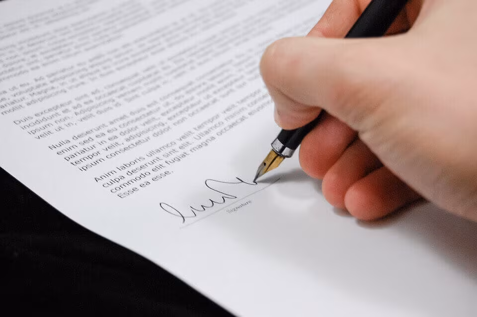 A hand signing a printed document with a fountain pen