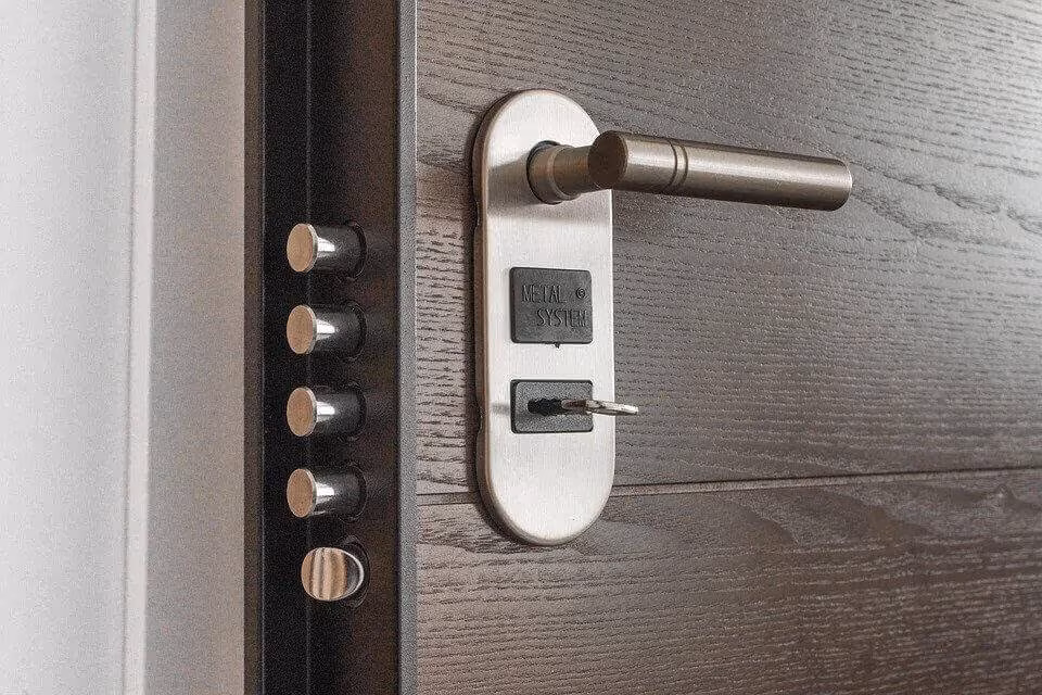 Close-up of a door handle with a keypad lock on a pale wooden door