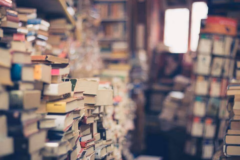 Towering stacks of books densely packed in a second-hand bookshop