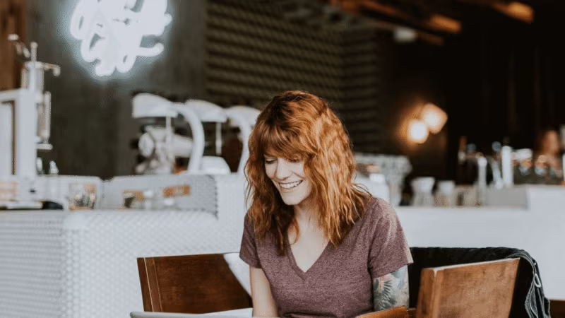 A woman working on a laptop at a table in a bright cafe