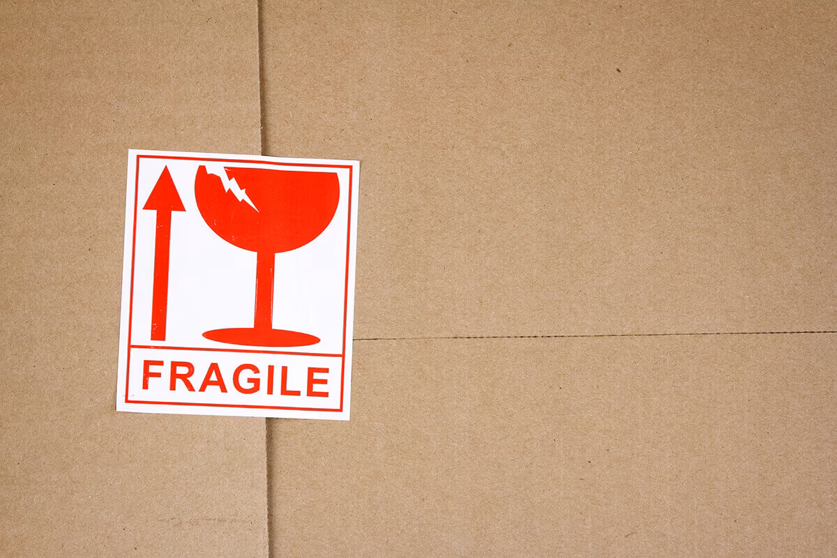 A red Fragile sticker with a broken-glass symbol on a cardboard box
