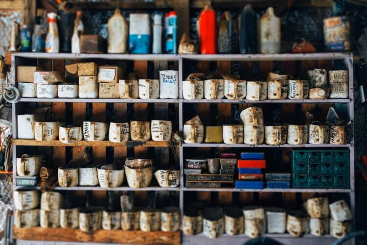 Cluttered garage shelving crowded with tins, bottles and jars