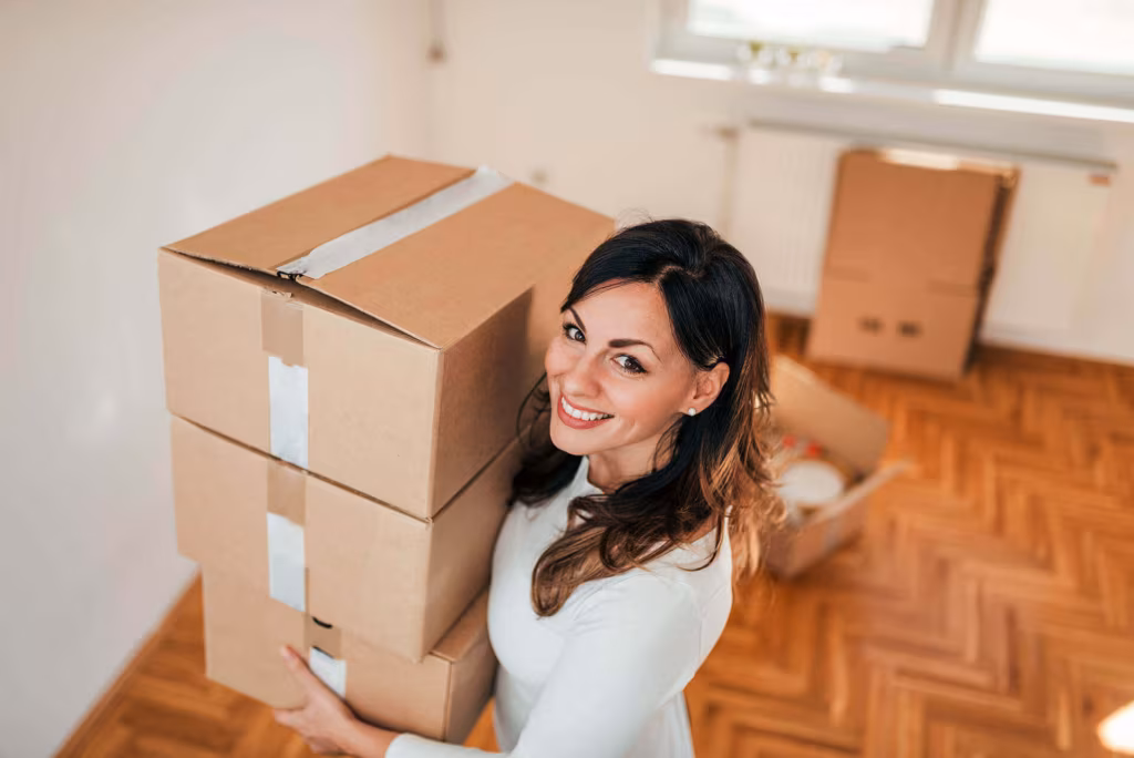 A woman carrying two stacked cardboard boxes