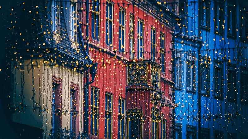 A row of buildings outlined in Christmas lights at night