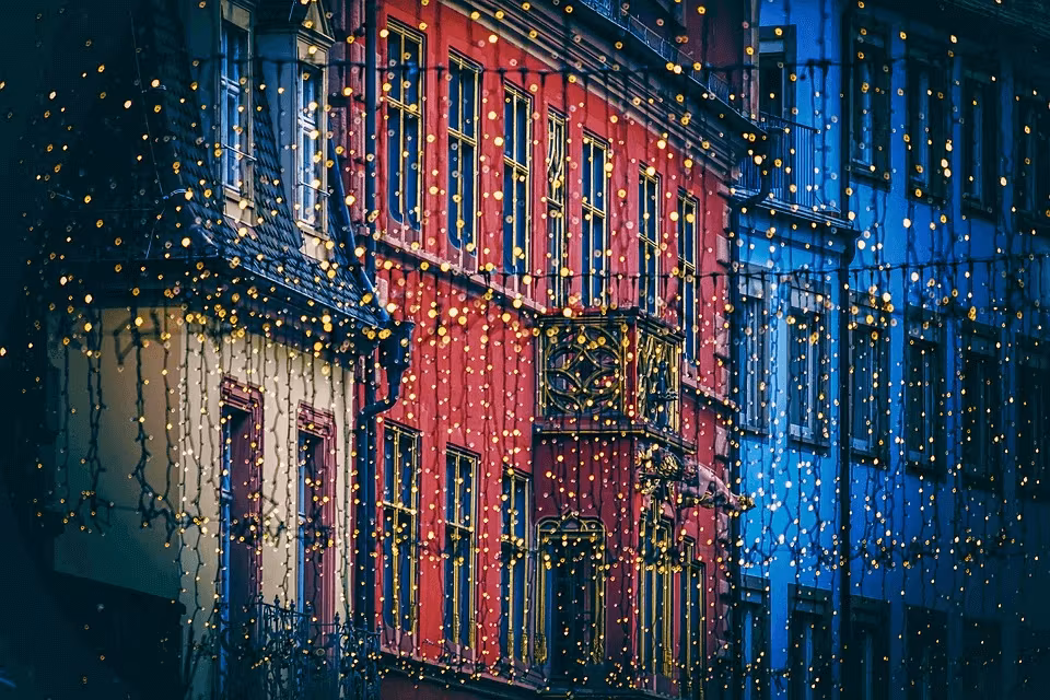 A row of buildings outlined in Christmas lights at night