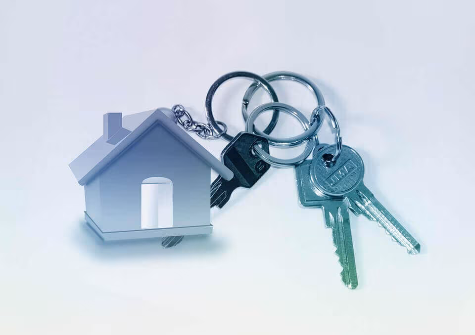 A house-shaped keyring with two keys on a pale surface