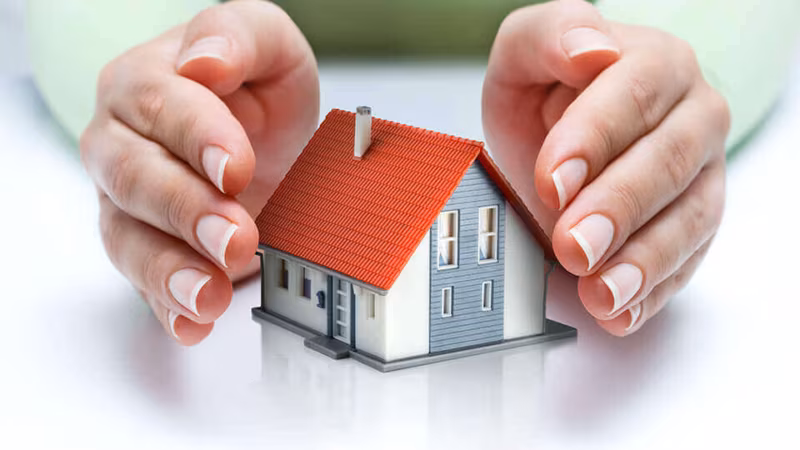 Two hands cupped protectively around a model house