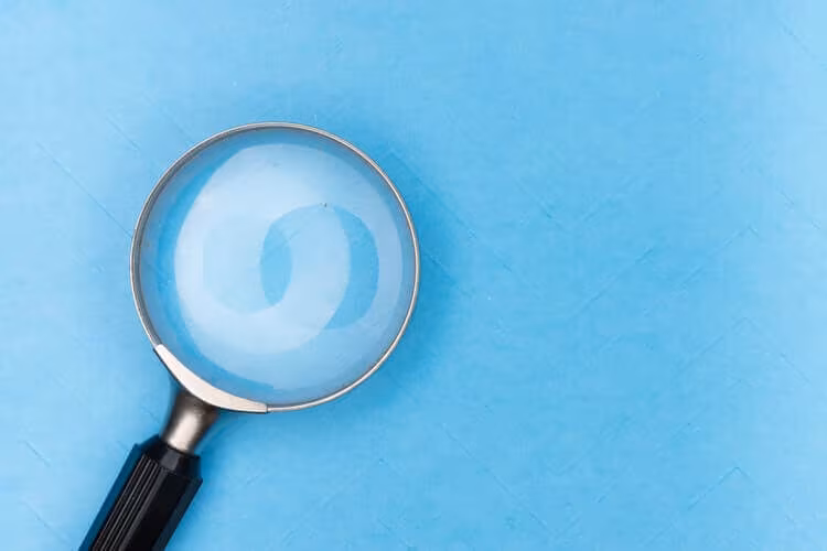A magnifying glass lying on a plain blue background