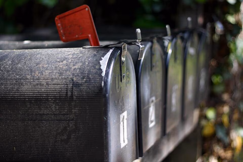 A row of black curbside mailboxes with one red flag raised