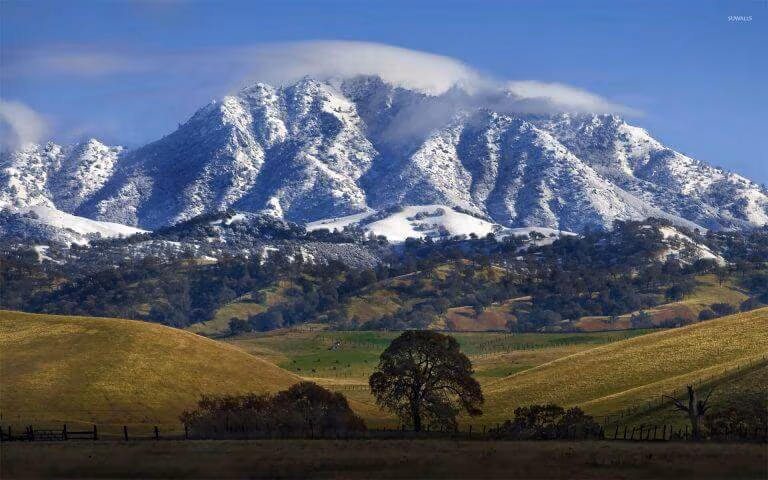 Mount Diablo under fresh snow above golden rolling hills