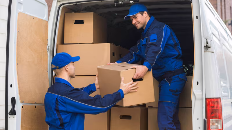 movers standing next to the pile of boxes unloading them