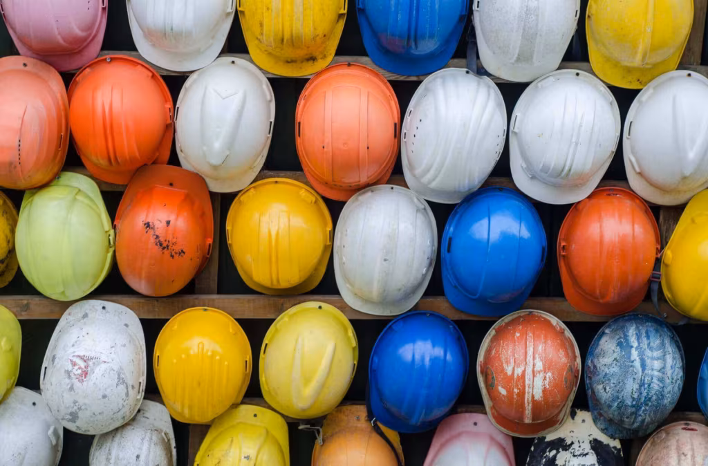 Rows of colored hard hats hanging on a wall