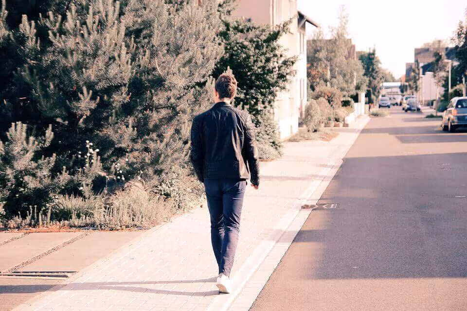 A person walking away along an empty suburban pavement