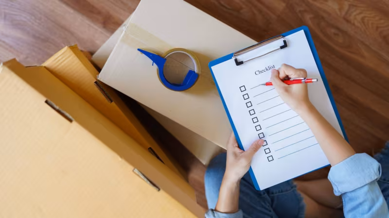 A person sitting cross-legged on the floor, writing on a clipboard