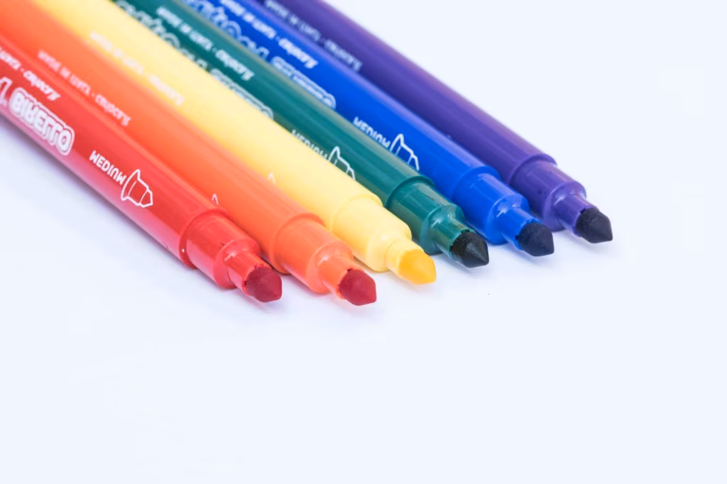 A row of colored marker pens with their caps off