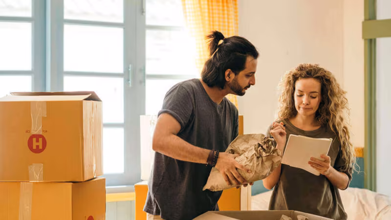 A couple unpacking crockery from a cardboard box