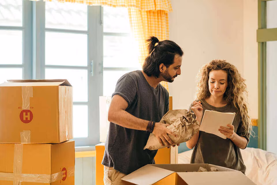 A couple unpacking crockery from a cardboard box