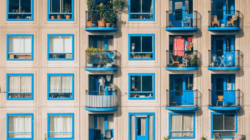 The facade of an apartment building with blue-framed windows and small balconies