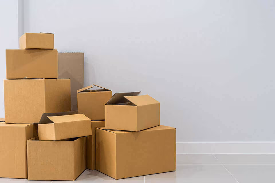 A stack of cardboard boxes of several sizes against a plain wall