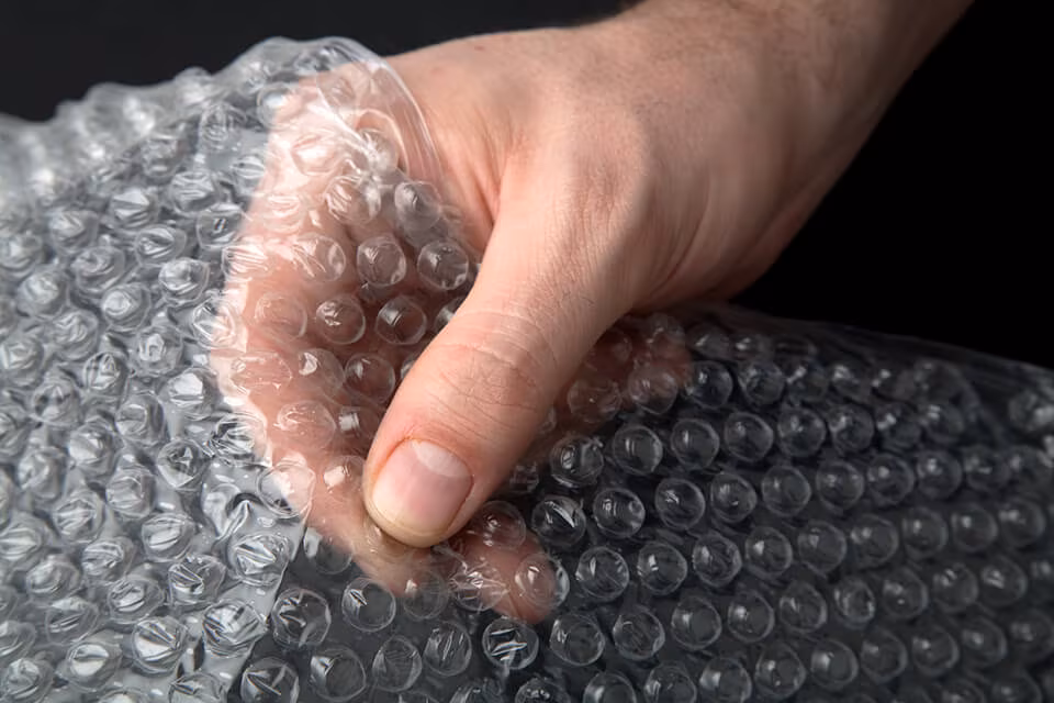 A hand squeezing a sheet of bubble wrap
