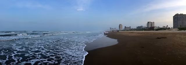 A flat beach at the water's edge with buildings in the distance