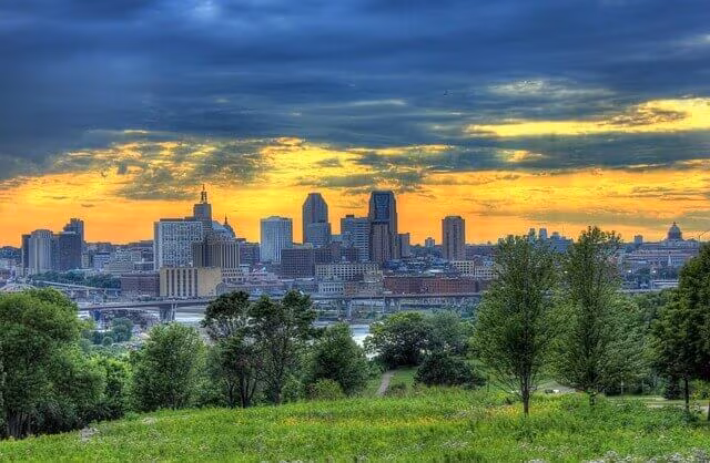 A city skyline at sunset seen across a green hillside