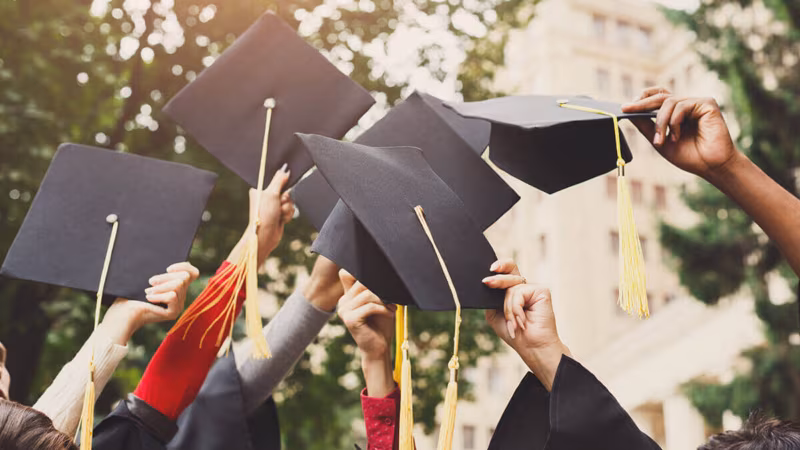 Graduates throwing their mortarboard caps in the air