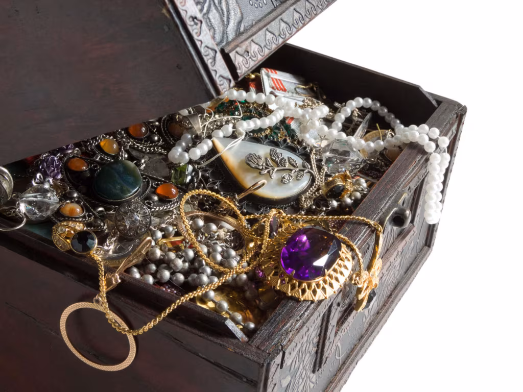 An open wooden jewellery box full of necklaces, rings and watches